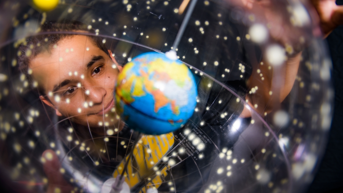 Young man smiling while observing a globe.