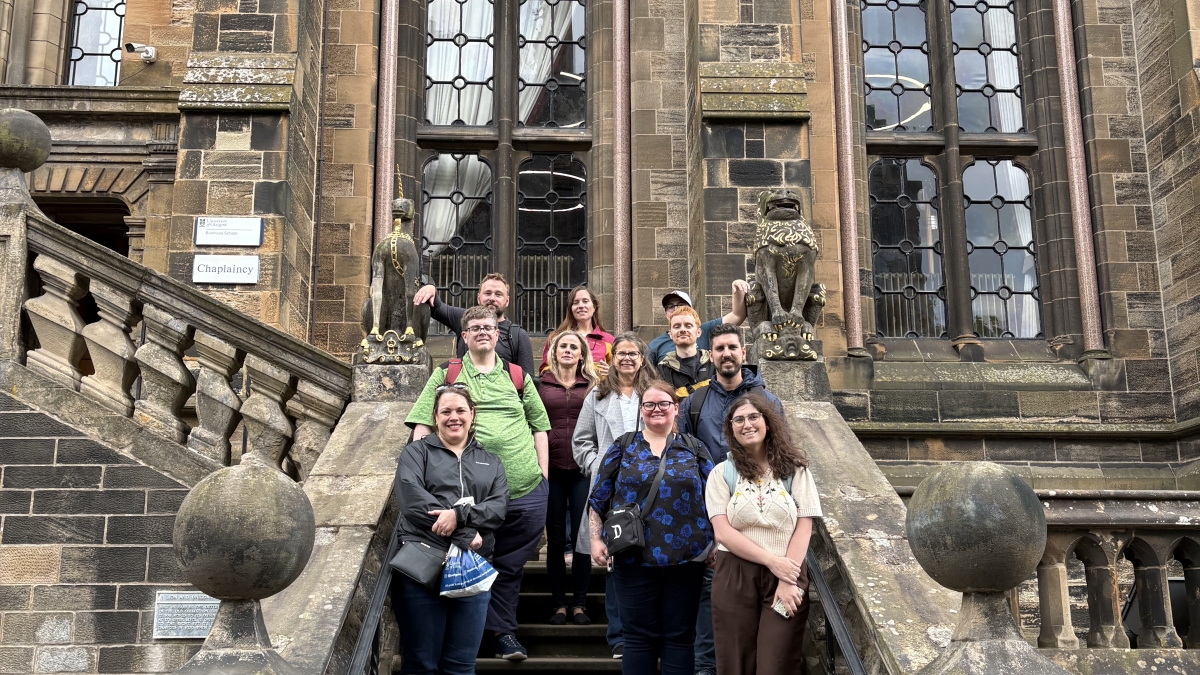 Group of students pose on a large stone staircase outside of an ornate old building.